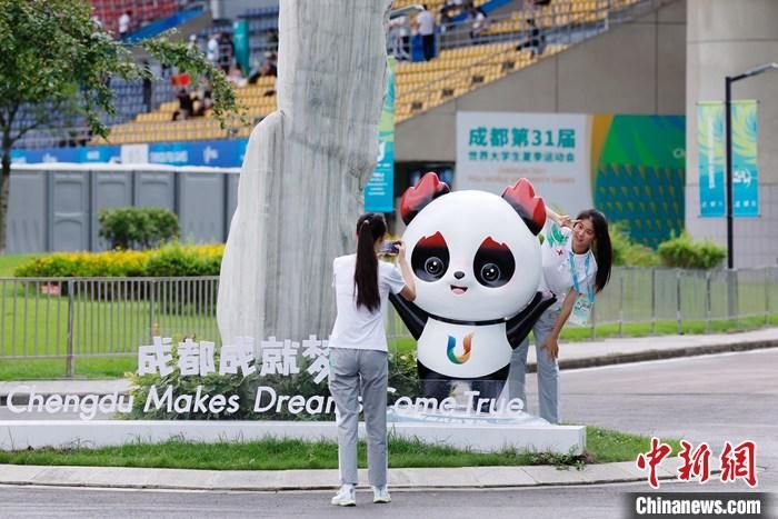 志愿者在比赛场馆外与吉祥物景观合影。</p><p>
    　　 中新社记者 韩海丹 摄